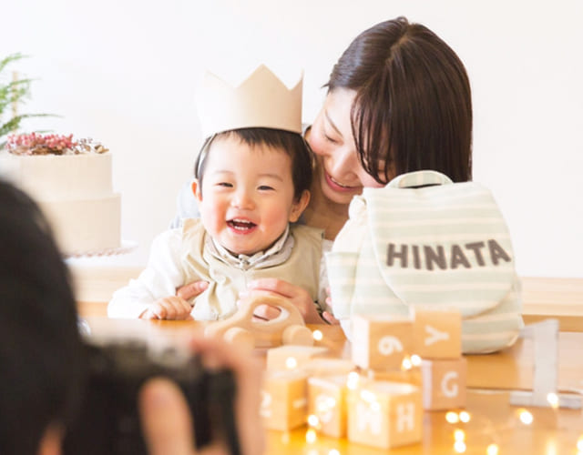 1歳の誕生日をお祝いする赤ちゃんとママ、名入れベビーリュックと一緒に記念撮影