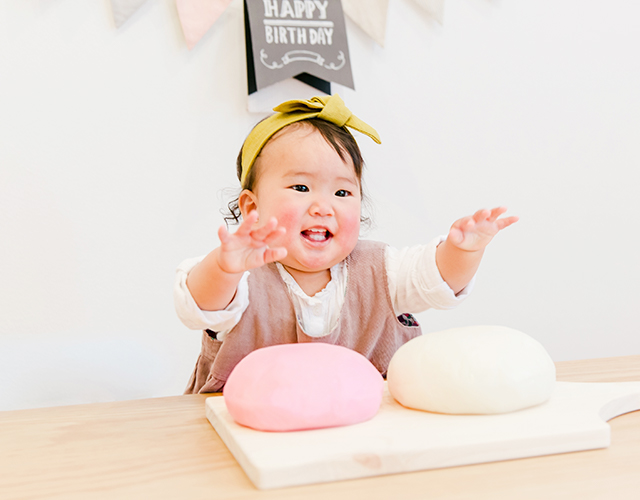 1歳のお祝いで一升餅を前に笑顔を見せる赤ちゃん